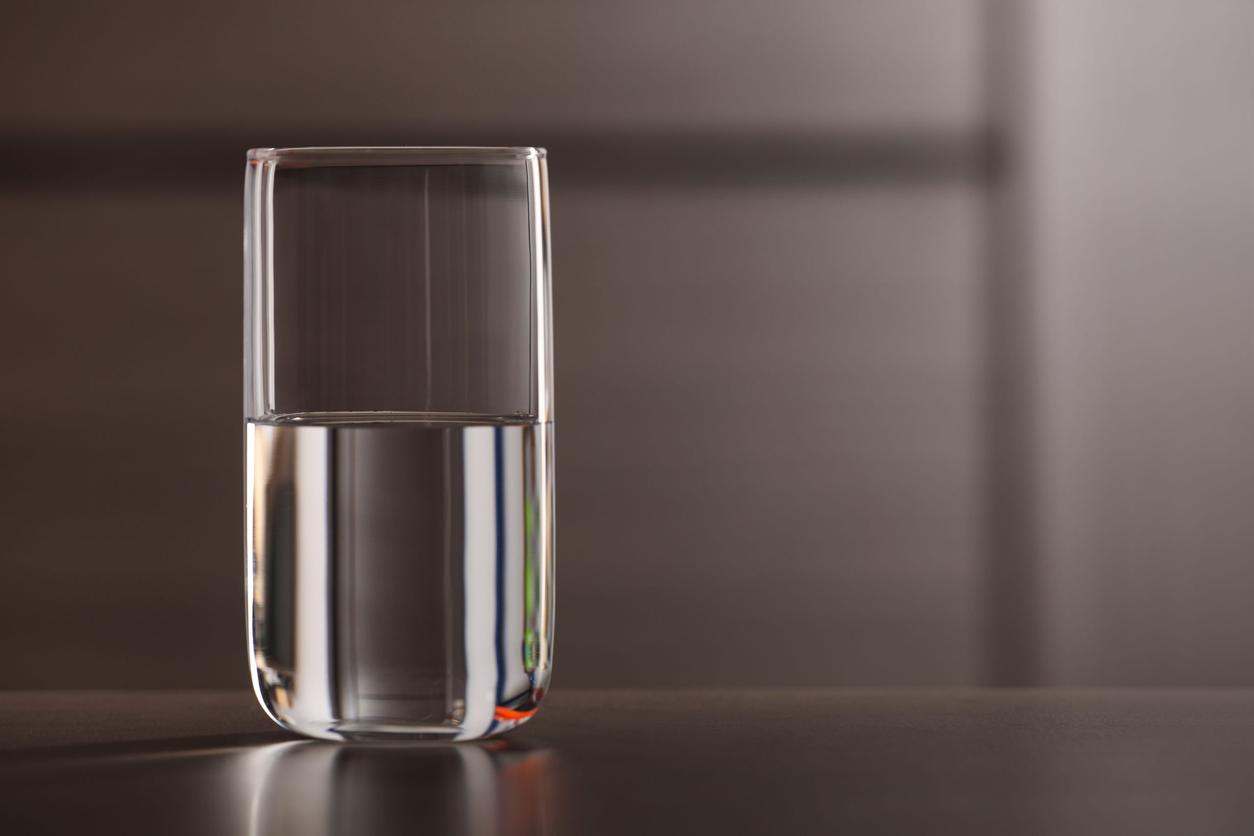 Glass of pure water on table against blurred background, space for text Glass of pure water on table against blurred background, space for text